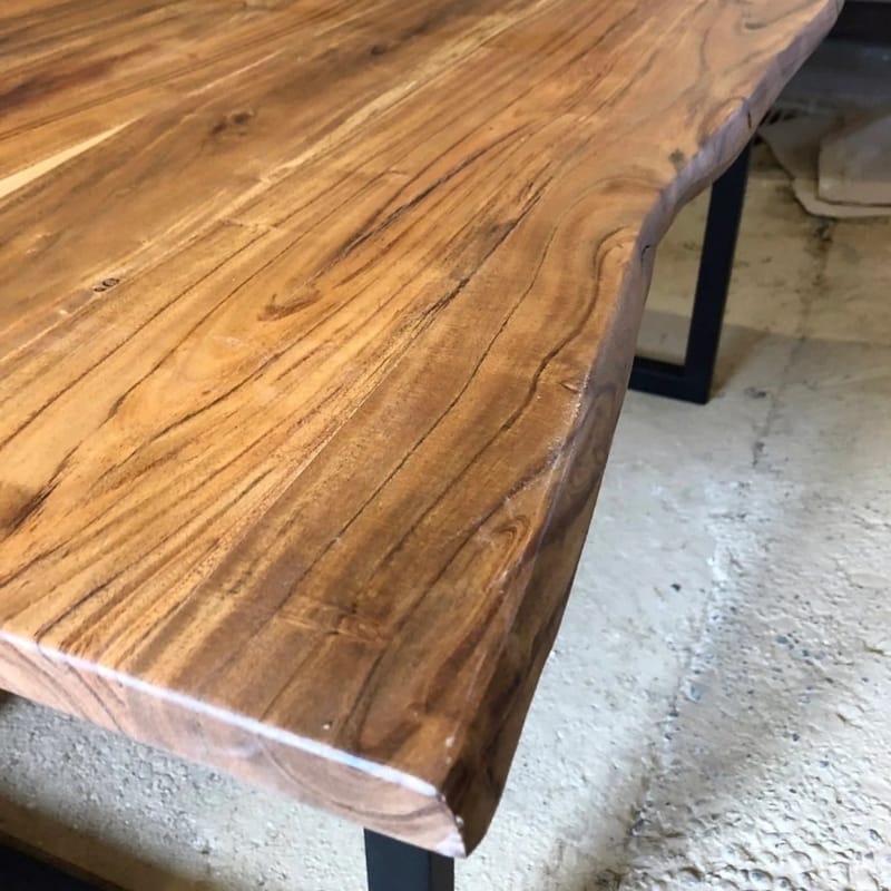 Black metal-framed dining table with acacia wood top and natural grain details